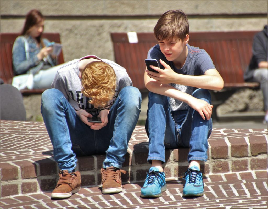 Two teenage boys with smartphones - a family traveling with kids has unique mobile internet challenges