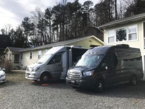 Two class B RVs parked in front of a home